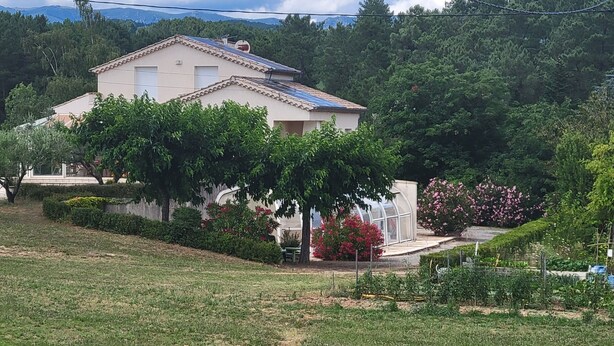 Una casa con jardín, invernadero y cielo despejado.