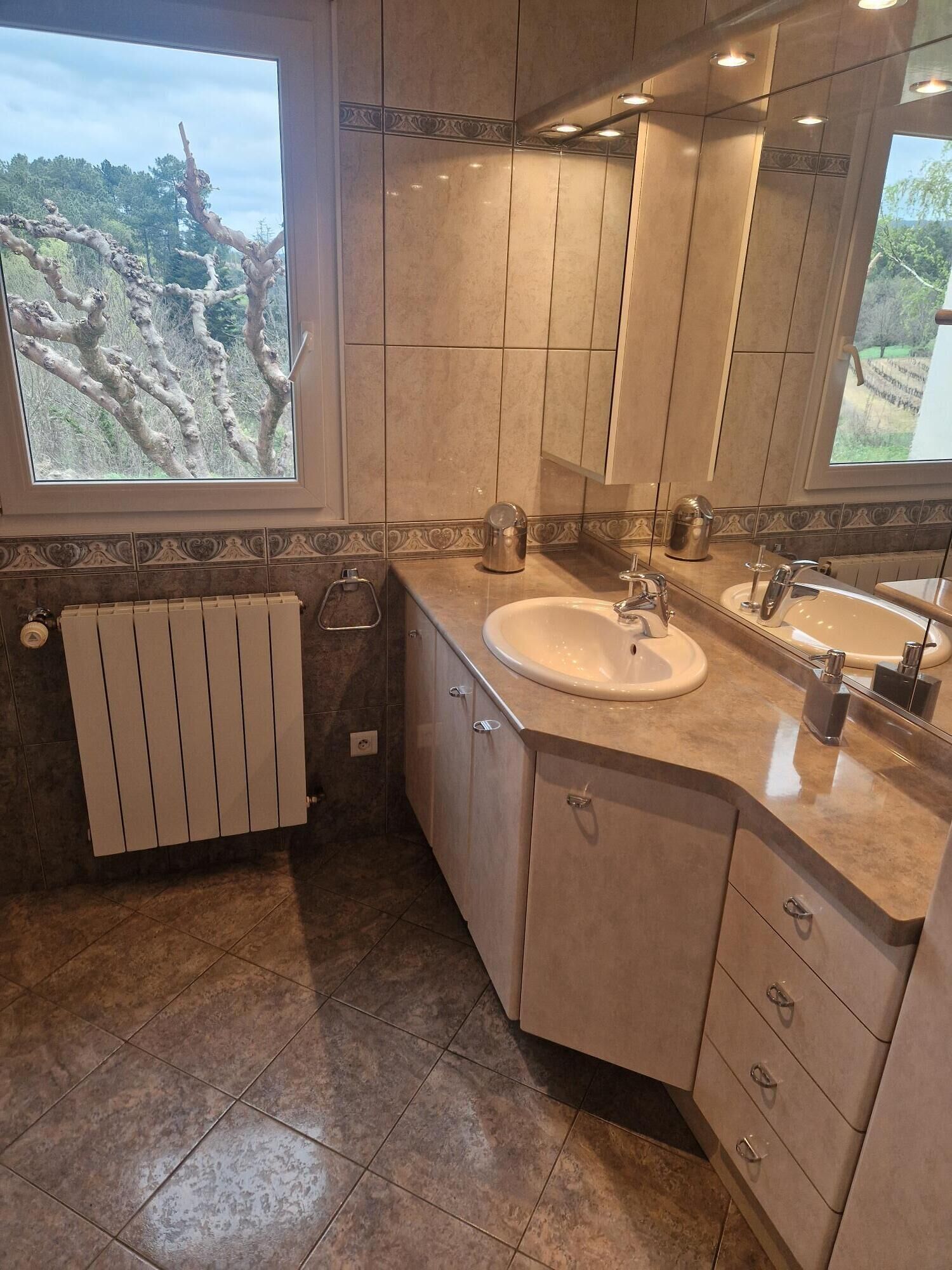 Une salle de bain moderne avec une grande fenêtre, un lavabo et un miroir.