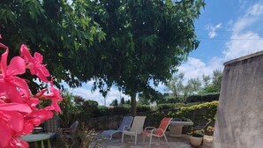 A patio area with stone flooring, outdoor furniture, and flowering plants. - Grande Maison Avec Piscine Chauffée et spa (Lablachère)