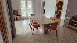 A dining area with a large wooden table and six chairs, a wooden cabinet with glass doors, and a tiled floor. - Grande Maison Avec Piscine Chauffée et spa (Lablachère)