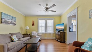 A living room with a sofa, armchair, coffee table, and a television.
