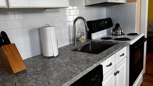 A kitchen with white cabinets, a microwave, a stove, and a dishwasher.