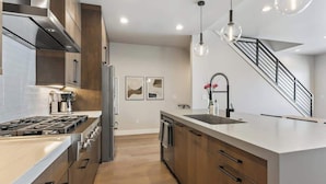 A modern kitchen with a stainless steel range, a built-in oven, and a large island with a sink.