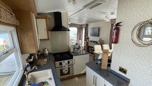 A compact kitchen with a sink, stove, and a small dining area. - 3 Bedroom Lodge, Close to Beach, Stunning Views, includes hot tub (Drummore)