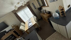 A compact kitchen with a sink, stove, and countertop. There is a mirror above the sink and a window with curtains. - 3 Bedroom Lodge, Close to Beach, Stunning Views, includes hot tub (Drummore)