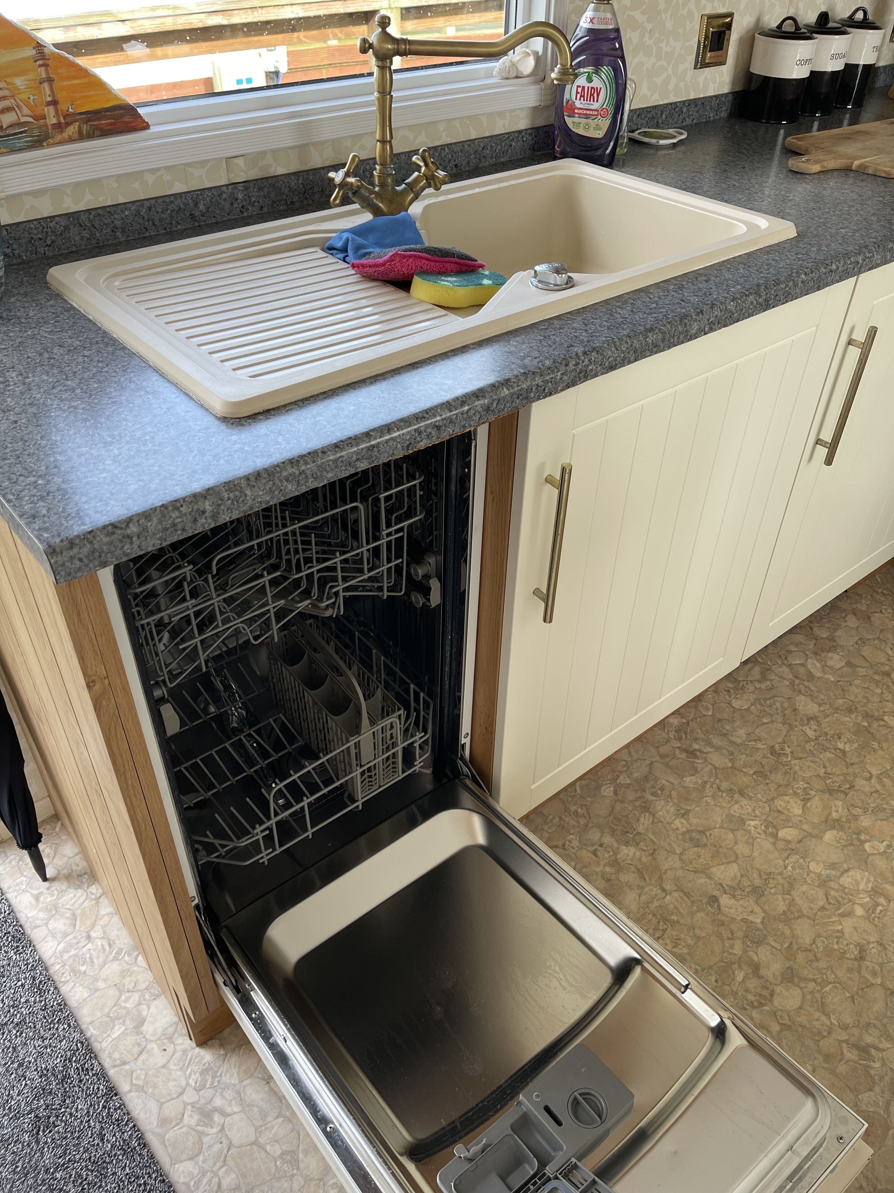 A kitchen with a built-in dishwasher, a sink with a faucet, and a window above the sink.
