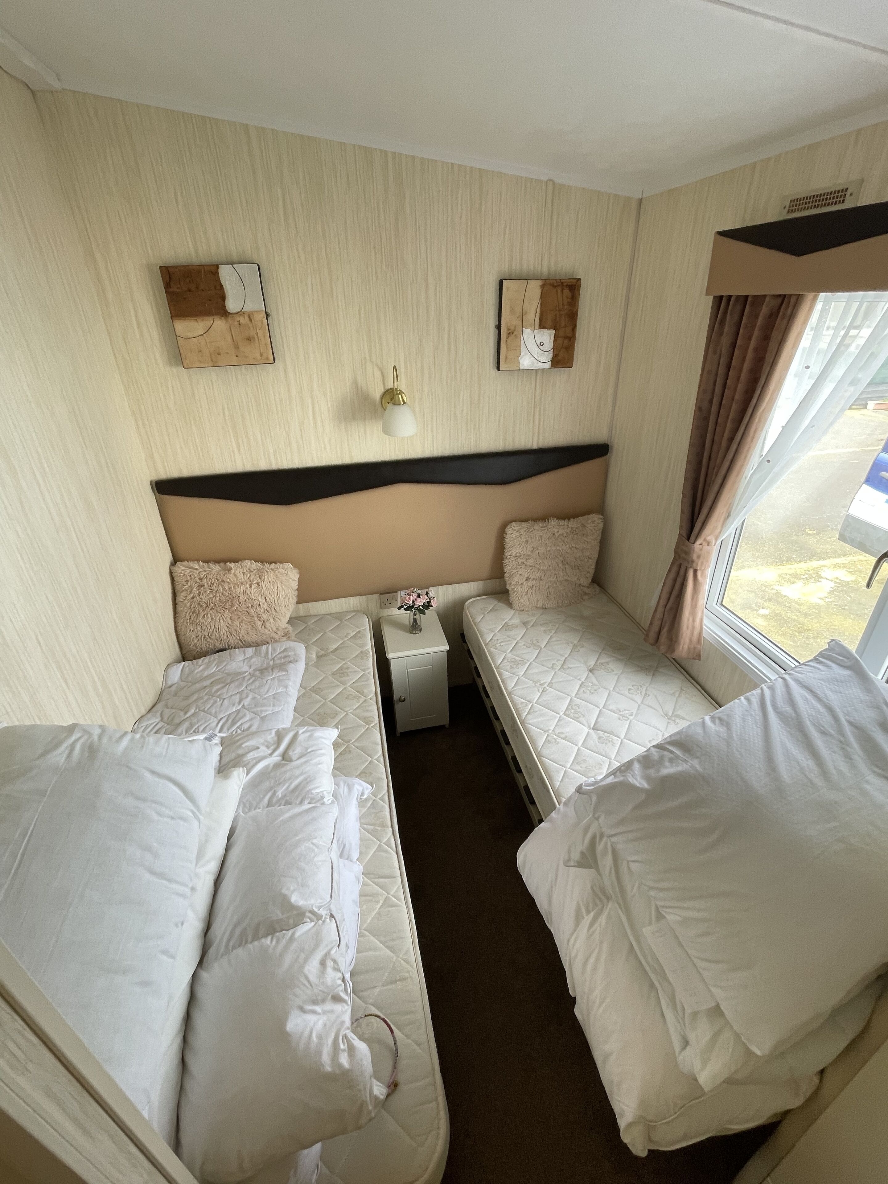 Ein kleines Zimmer mit zwei Betten, einem Tisch und einer Wandleuchte.