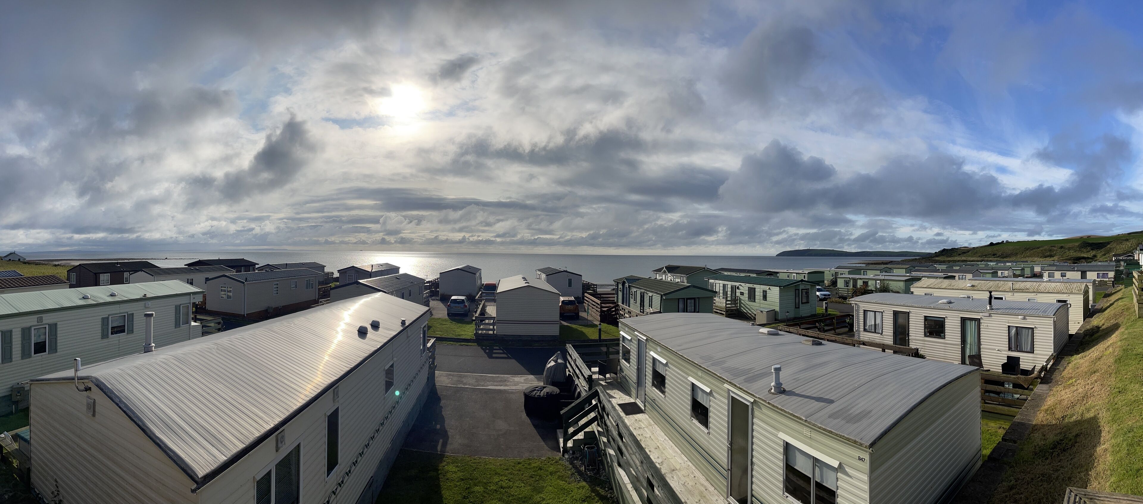 A row of mobile homes with a view of the sea and cloudy sky.