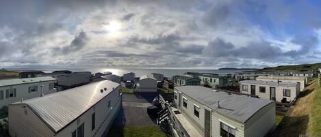 A row of mobile homes with a view of the sea and cloudy sky.