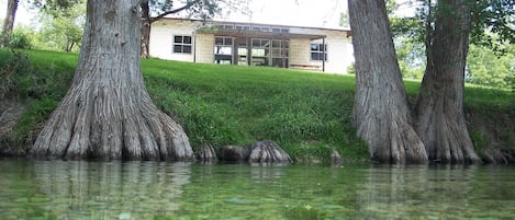 Une maison à la façade en pierre, entourée d’arbres et d’une pelouse.