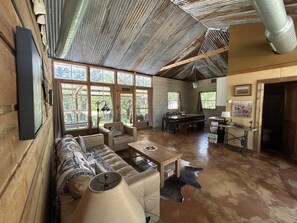 A spacious living area with a sofa, chairs, a dining table, and a kitchen area.