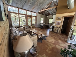 Um interior rústico com sofá, poltronas, mesa de jantar e área de cozinha.