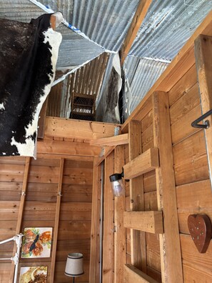 A rustic wooden interior with a cowhide, wooden shelves, a lantern, and a heart-shaped decoration.
