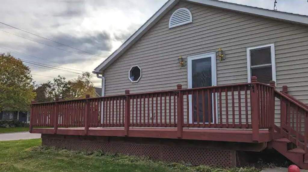 Une maison à deux étages avec une terrasse rouge et un petit porche.