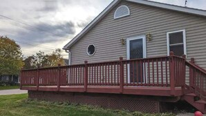 Une maison à deux étages avec une terrasse rouge et un petit porche.