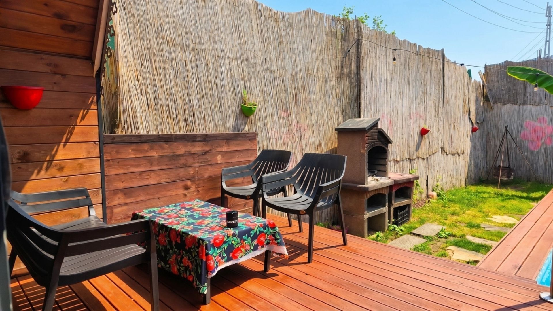 Una terraza de madera con mesa y sillas, una parrilla de barbacoa y una valla de madera.