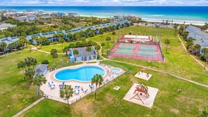 Ett semesterhotell med pool, tennisbanor och utsikt över stranden.