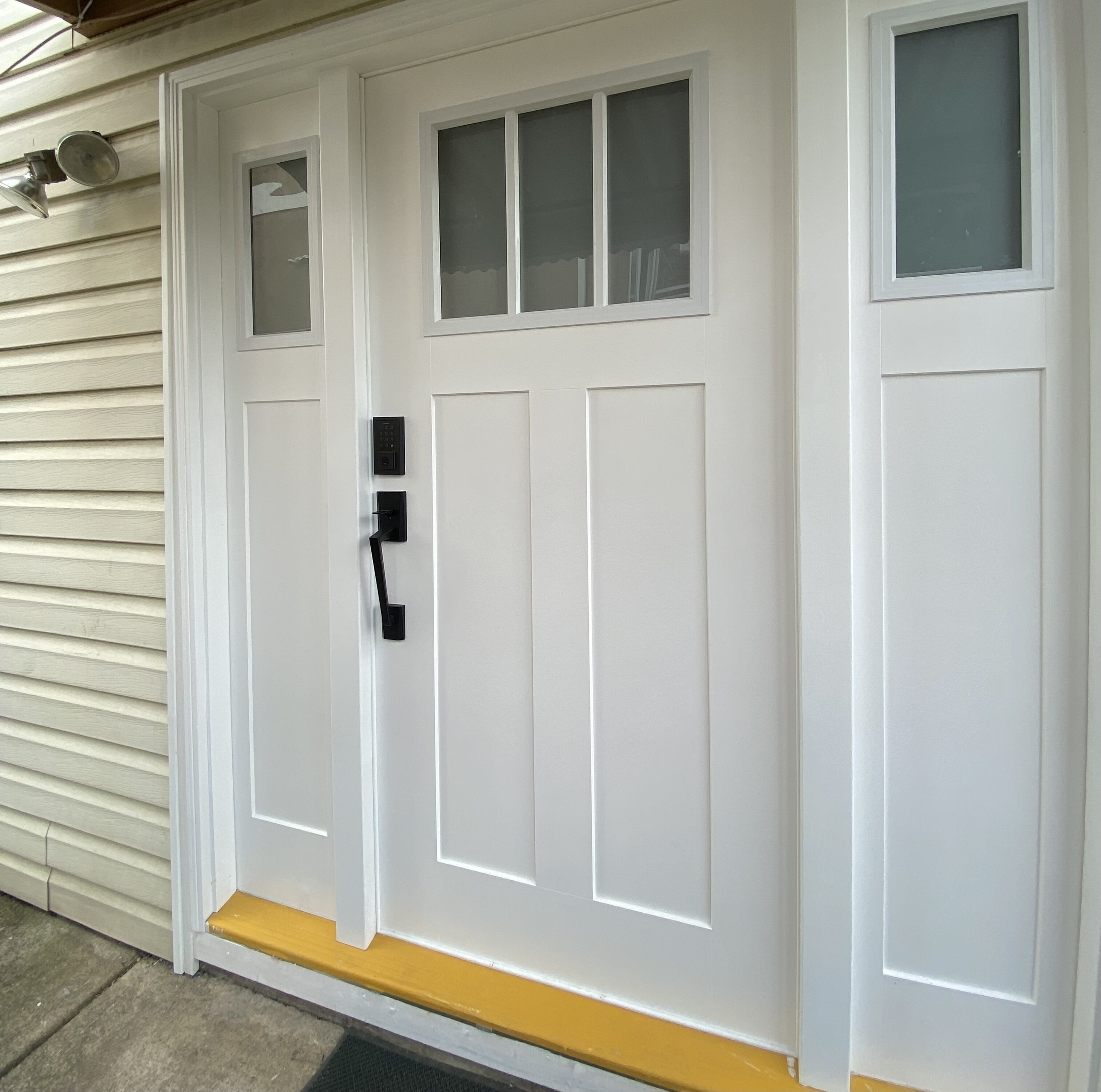 A white front door with a keypad lock, a small window above it, and a yellow threshold.