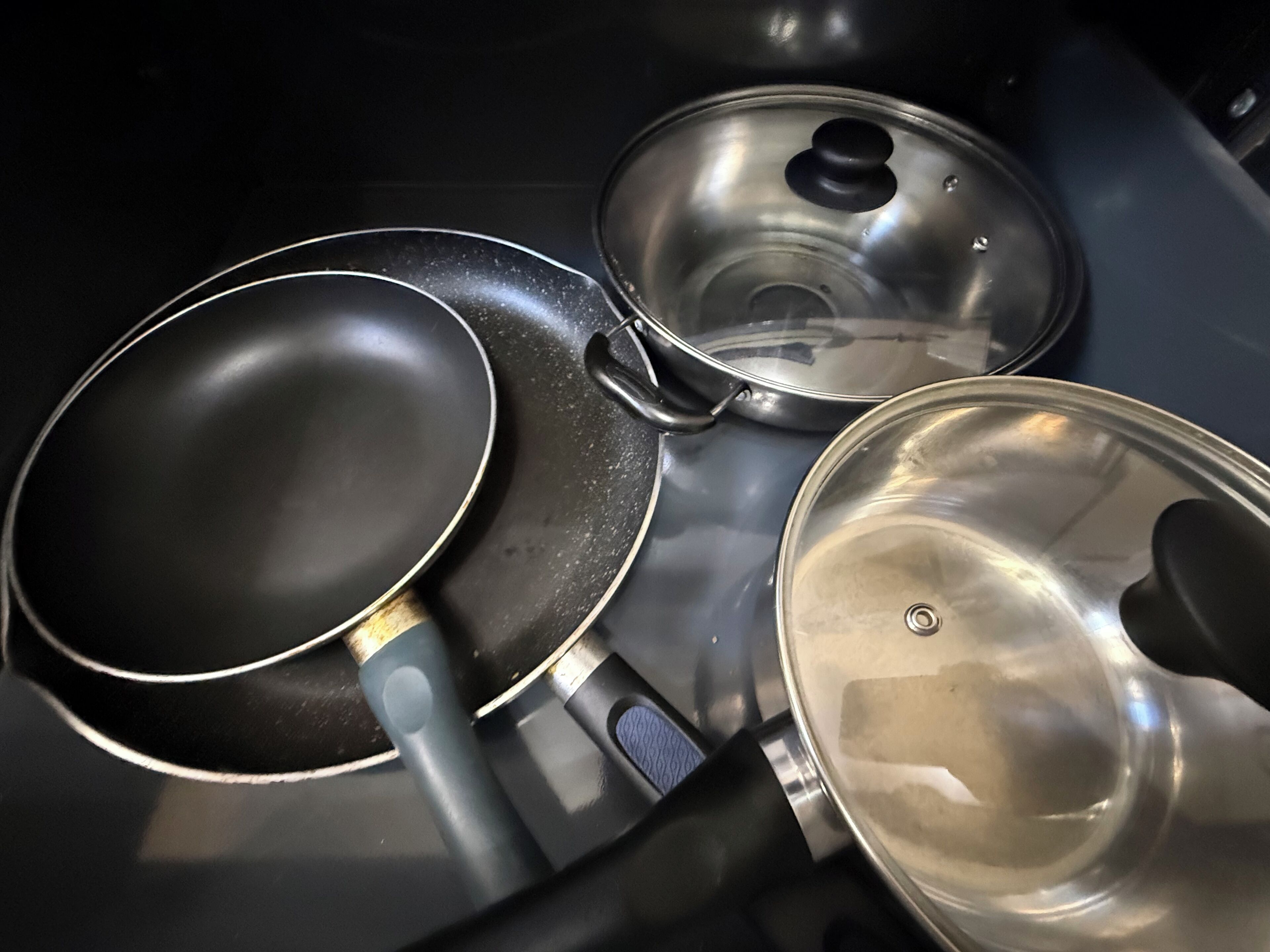 A kitchen with a stove, a frying pan, and a pot.