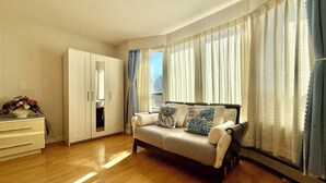 Une chambre à coucher comprenant un lit, une armoire, une commode et une fenêtre avec des rideaux.