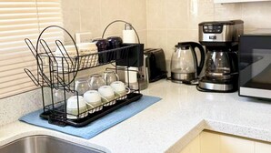 Une cuisine équipée d’un égouttoir, d’un grille-pain, d’une machine à café et d’un four à micro-ondes.