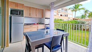 Una cucina compatta con elettrodomestici moderni, un tavolo da pranzo in vetro e un balcone con vista su una zona residenziale.