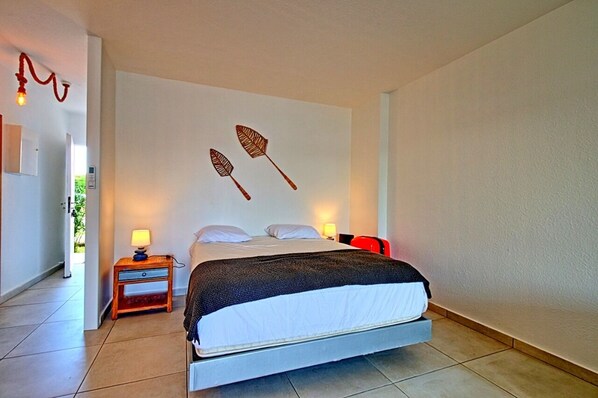 A bedroom with a bed, bedside tables, and wall art.
