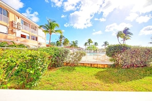 A hotel with a pool, surrounded by lush greenery and palm trees.