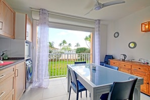 A modern kitchen with a dining area, a washing machine, and a view of the outdoors.