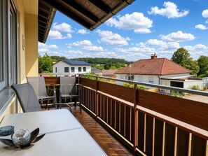 A balcony with a table and chairs, a decorative glass sphere, and a view of houses and trees.