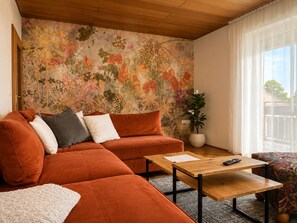 A living room with a sectional sofa, a coffee table, and a potted plant.