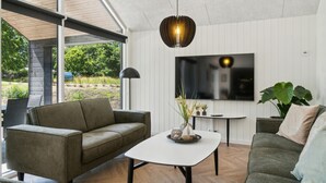 Un soggiorno moderno con un divano, un tavolino da caffè e una TV fissata al muro.