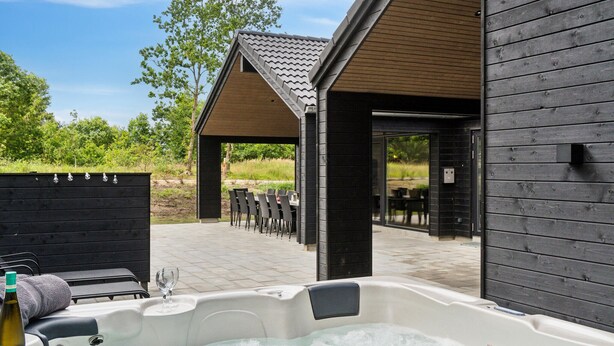 Area idromassaggio con vasca, veranda in legno, posti a sedere all'aperto e patio coperto.