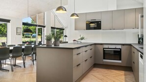 Una cucina moderna con un'isola grande, elettrodomestici integrati e luci a sospensione.