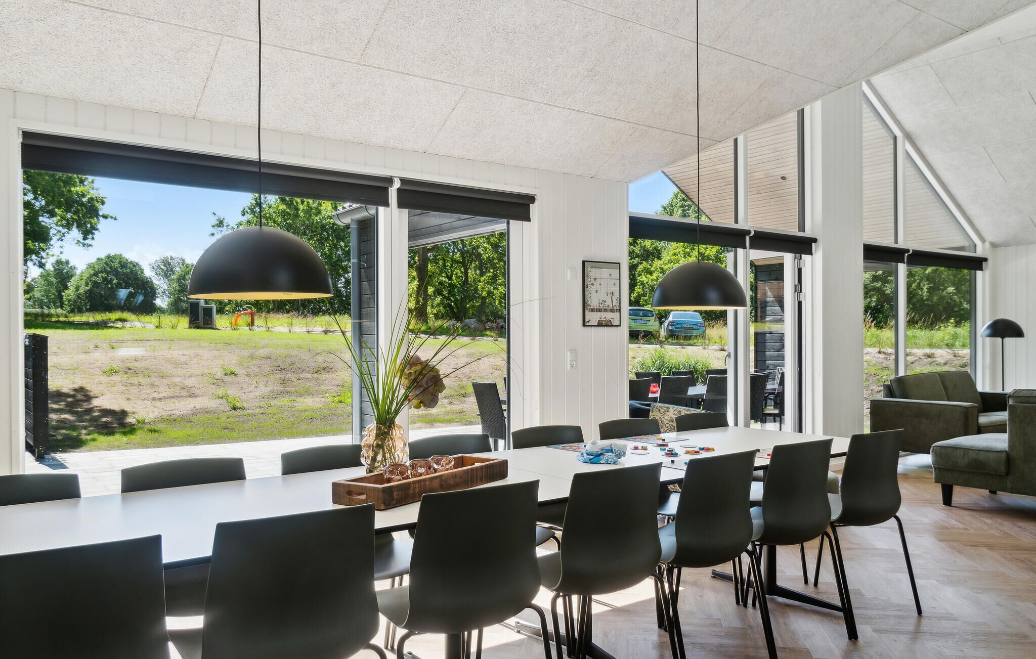 A spacious dining area with a long table, black chairs, and large windows offering a view of the outdoors.