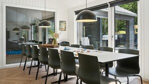 Un'area pranzo moderna con un tavolo grande, sedie nere e lampade a sospensione.