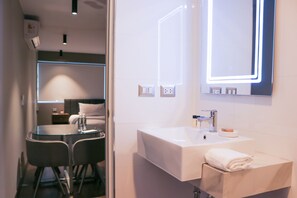 A modern bathroom with a white sink, mirror, and two chairs. - Camino Real by Wynwood House (Lima)