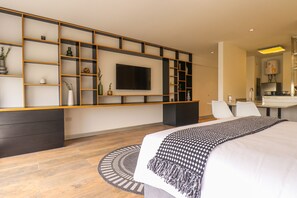 A modern hotel room with a large bed, a TV mounted on a wall, a dining area, and a kitchen. - Camino Real by Wynwood House (Lima)