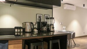 Eine moderne Küche mit dunkler Arbeitsplatte, Edelstahlgeräten und einer Glasinsel mit Barhocker.