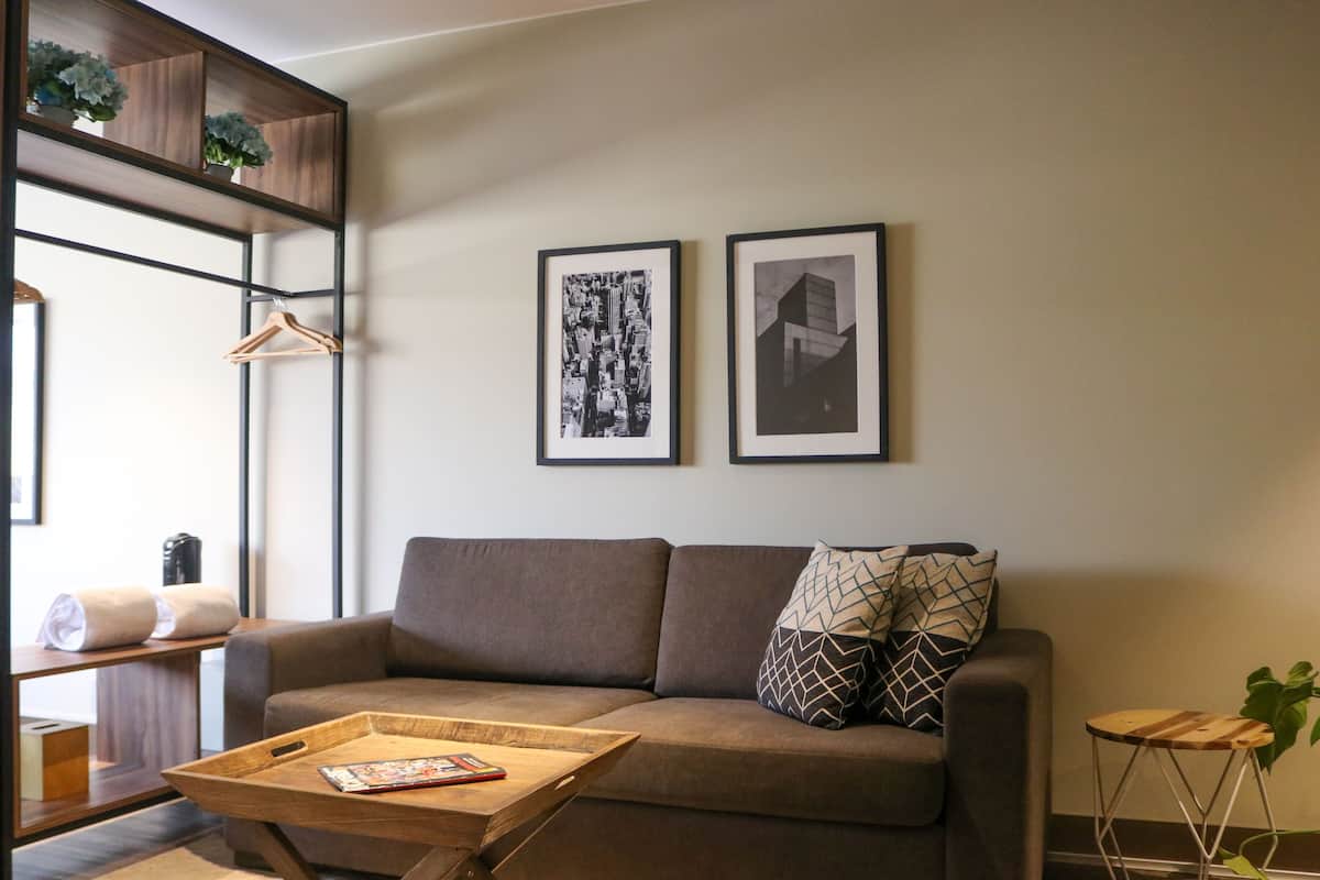 Uma sala de estar moderna com um sofá, uma mesa de centro de madeira e duas fotos emolduradas na parede.