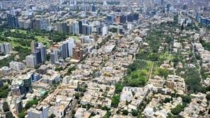 An aerial view of a densely populated urban area with high-rise buildings, green spaces, and a mix of residential and commercial structures. - Camino Real by Wynwood House (Lima)