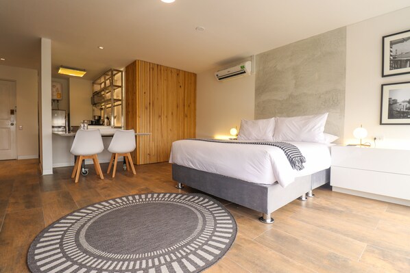 A modern bedroom with a bed, bedside table, and a small desk area with chairs. - Camino Real by Wynwood House (Lima)