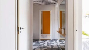 A hotel hallway with a geometric patterned floor, a wooden door, and a bed visible through an open door. - Perfect apartment near the beach + 6 free bikes (Pärnu)