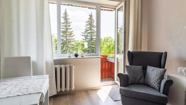 A modern living room with a sofa, a table, and a window with a view of trees. - Perfect apartment near the beach + 6 free bikes (Pärnu)