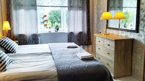 A bedroom with a bed, bedside lamps, a dresser, and a window with curtains. - Perfect apartment near the beach + 6 free bikes (Pärnu)