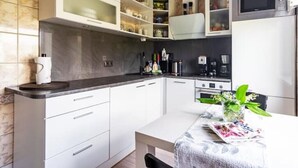 A modern kitchen with white cabinets, a black countertop, and a dining table with a vase of flowers. - Perfect apartment near the beach + 6 free bikes (Pärnu)