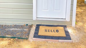 A white door with a window above it, a doormat with "HELLO" on it, and a small porch light. - Private Dallas/Bishop Arts Retreat  (Dallas)