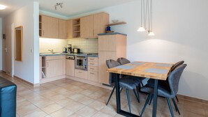 Una cocina moderna con armarios de madera, una mesa de comedor con sillas y piso de baldosas.