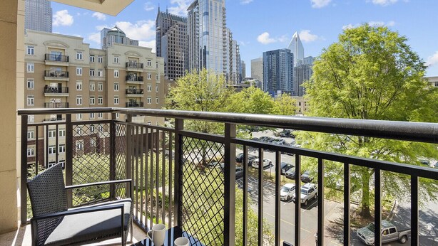 A balcony with a view of a cityscape, including high-rise buildings and a parking area. - Beautiful Blue | Spacious, Free Parking, View, Gym (Charlotte)