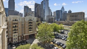 A high-rise building with a modern design, surrounded by other tall buildings, a parking lot, and a tree-lined street. - Beautiful Blue | Spacious, Free Parking, View, Gym (Charlotte)